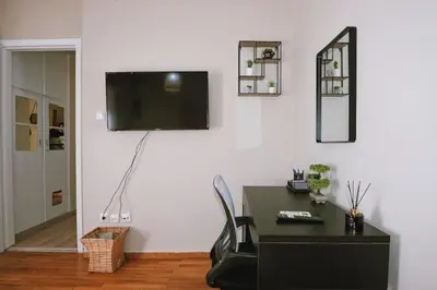 a room with a desk and a television on a wall at Cozy Apartment in the heart of Athens! in Athens