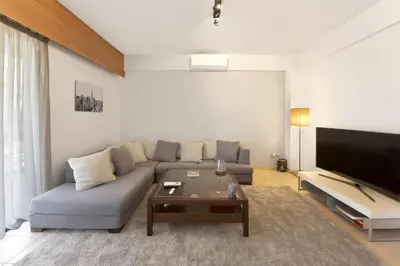 a living room with a couch and a flat screen tv at Seascape Modern Vouliagmeni Apt near Beaches in Athens