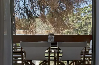 a table with two chairs and a wine glass on it at Seascape Modern Vouliagmeni Apt near Beaches in Athens