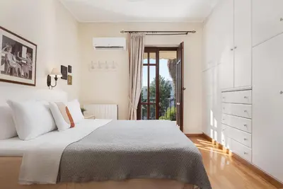a white bedroom with a bed and a window at Voula Riviera Apartment in Athens