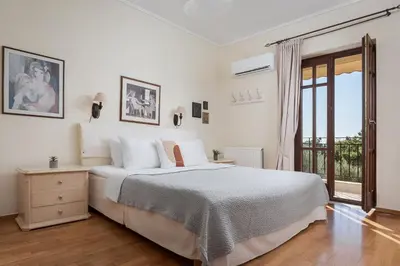 a white bedroom with a large bed and a window at Voula Riviera Apartment in Athens