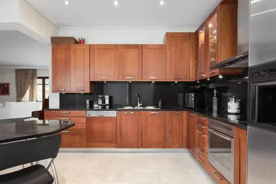 a kitchen with wooden cabinets and black counter tops at Voula Riviera Apartment in Athens