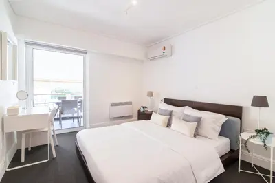 a white bedroom with a large bed and a desk at Sun & Sea Suite, Kavouri in Athens