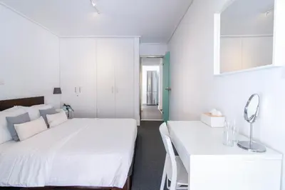 a white bedroom with two beds and a table at Sun & Sea Suite, Kavouri in Athens