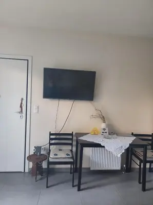 a room with a table and chairs and a tv on the wall at Pegasus cosy house in Athens