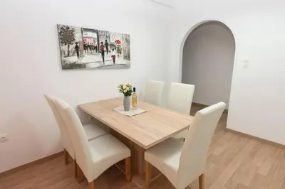 a dining room with a wooden table and white chairs at Spacious flat 10min from subway stations (BODA_B3) in Athens