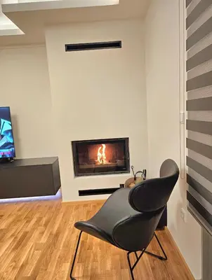 a black chair in a living room with a fireplace at Filothei Luxury Apartment 110m2 in Athens