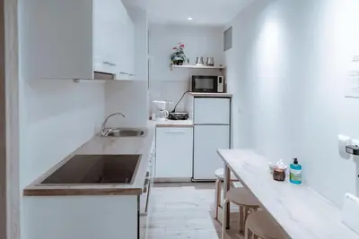 a white kitchen with a sink and a counter at Acropolis Museum Stylish Apartments in Athens