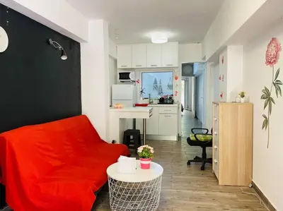 a living room with a red couch and a kitchen at A comfortable apartment to you in Athens