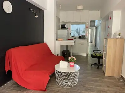a living room with a red bed and a kitchen at A comfortable apartment to you in Athens