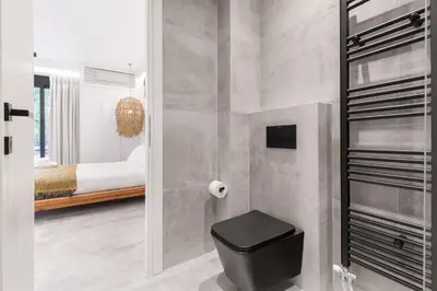 a bathroom with a black toilet and a bedroom at Nana's Residence in Athens
