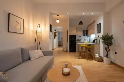a living room with a gray couch and a kitchen at The Heart Of Athens in Athens
