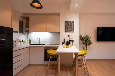 a kitchen with a white table and yellow stools at The Heart Of Athens in Athens
