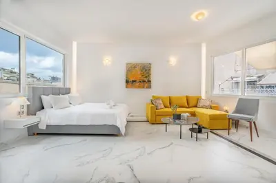 a white bedroom with a bed and a couch at Olvar Suites in Athens