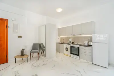 a kitchen with white cabinets and a marble floor at Olvar Suites in Athens
