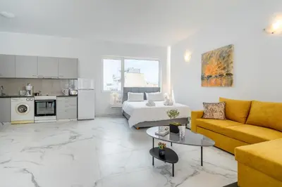 a white living room with a bed and a couch at Olvar Suites in Athens