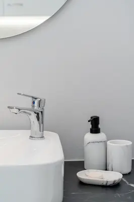 a sink with a soap dispenser and a bottle of soap at Olvar Suites in Athens