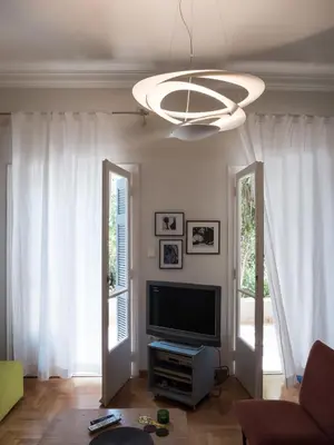 a living room with a television and a chandelier at 90m2 lovely 1-bedroom apartment in Paleo Faliro in Athens