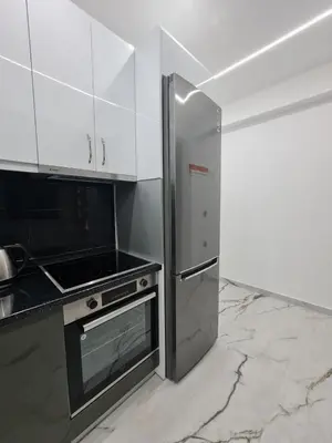 a kitchen with a stainless steel refrigerator and white cabinets at Luxury apartment in Attiki in Athens