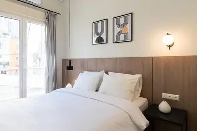 a bedroom with a white bed and a window at Callirhoē Luxury 2BD Acropolis Apartment in Athens