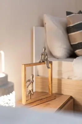 a small wooden clock on a table next to a bed at LIV - Vintage Acropolis Apartment in Athens