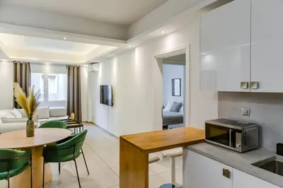 a kitchen and living room with a table and a microwave at SYNTAGMA VOULIS STREET MODERN APARTMENT in Athens