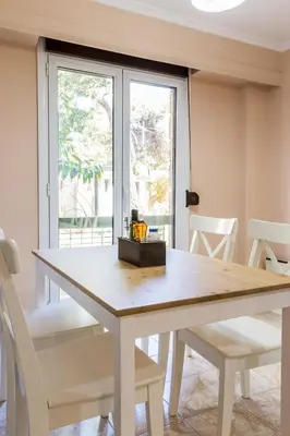 a dining room table with white chairs and a window at Glyfada 2 bedrooms 4 persons apartment by MPS in Athens