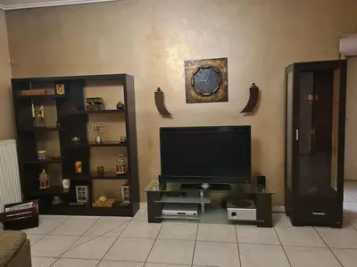 a living room with a flat screen tv and shelves at Άνετο, μεγάλο σπίτι κοντά στο μετρό in Piraeus