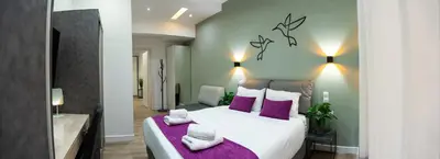 a bedroom with a large white bed with purple pillows at Romeo & Juliet In the heart of Athens in Athens