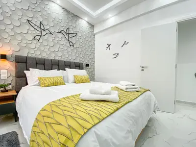 a bedroom with a large bed with yellow and white sheets at King Davids Suite Athens finest! in Athens