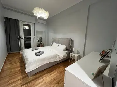 a bedroom with a white bed and a wooden floor at Acropolis Casa 2bdr/2bthr w/hot tub-3mins to plaka in Athens