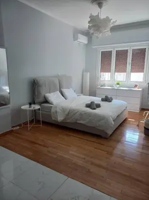 a white bedroom with a bed and a wooden floor at Acropolis Casa 2bdr/2bthr w/hot tub-3mins to plaka in Athens