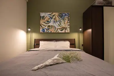 a bedroom with a bed with a pillow and a painting at 15 minutes from Acropolis apartment in Athens
