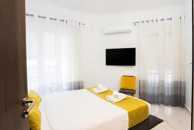 a white bedroom with a bed and a tv at Paradise Syntagma Family Apartment in Athens