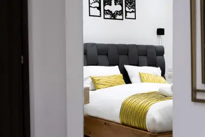 a bed with a black headboard and yellow pillows at Paradise Syntagma Family Apartment in Athens