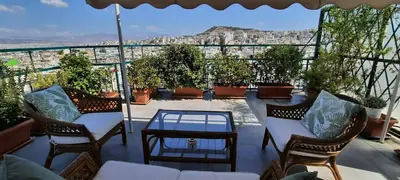 a balcony with chairs and a table and a view of a city at Taratsaki in Athens