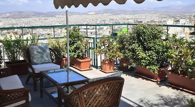 a balcony with a table and chairs and plants at Taratsaki in Athens