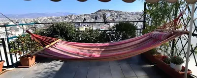 a hammock on a balcony with a view of a city at Taratsaki in Athens