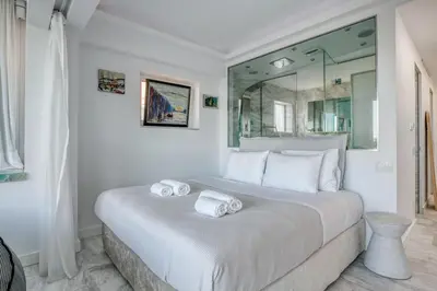 a white bedroom with a large bed with towels on it at South Blue Luxury Apartment in Vouliagmeni in Athens