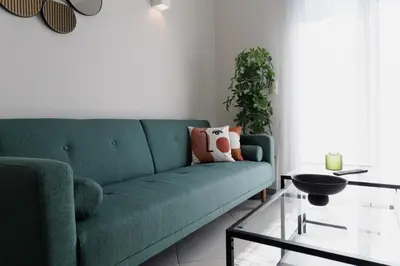 a living room with a green couch and a glass table at Sunny & Modern apt for 3 persons in Athens