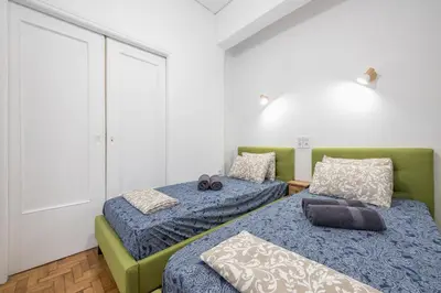 a bedroom with two beds and a green couch at Stylish Luxury Apartment near Acropolis at Syngrou-Fix metro station in Athens