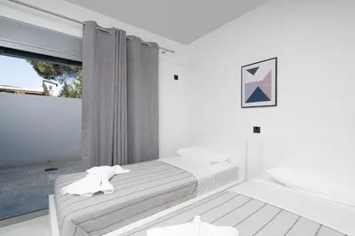 a white bedroom with a bed and a window at Luna Apartment by A&D Properties in Porto Rafti