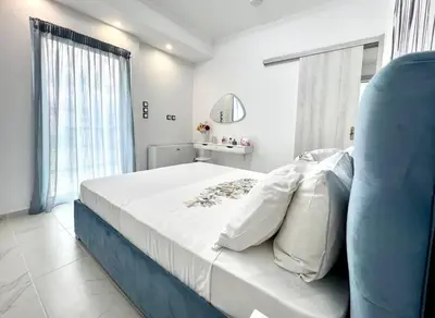 a bedroom with a large bed and a blue chair at Evilion Maisonette in Athens in Athens
