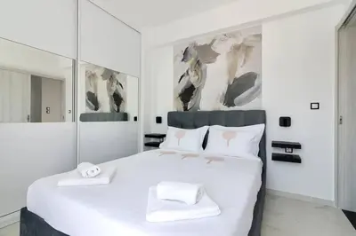 a white bedroom with a large white bed with two towels at Evilion Maisonette in Athens in Athens