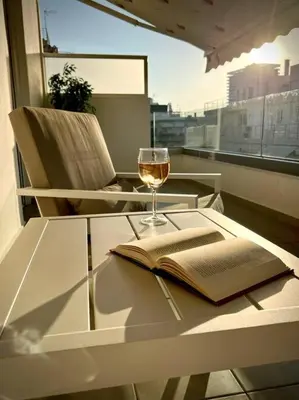 a glass table with a book and a glass of wine at Evilion Maisonette in Athens in Athens