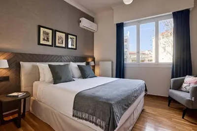 a bedroom with a bed and a chair and a window at Acropolis Museum Grand Residence in Athens