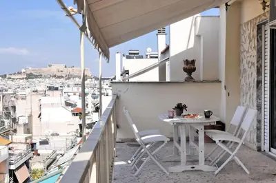 a table and chairs on a balcony with a view at 2 level apartment with terrace and Acropolis view in Athens