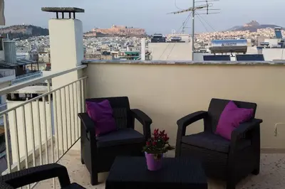 two chairs and a table on a balcony with purple pillows at 2 level apartment with terrace and Acropolis view in Athens