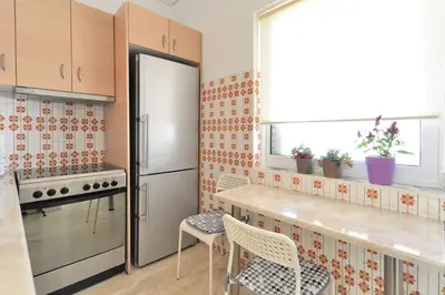 a kitchen with a refrigerator and a table and chairs at 2 level apartment with terrace and Acropolis view in Athens