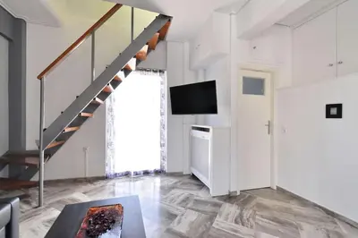a living room with a staircase and a television at 2 level apartment with terrace and Acropolis view in Athens
